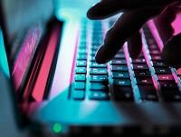 A person typing on a dimly lit computer keyboard